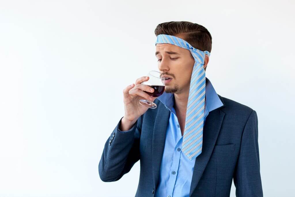 Drunk businessman with headache drinking red wine